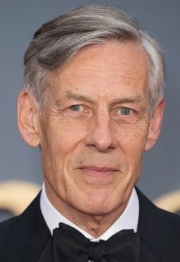 Douglas Reith Posing for a photoshoot wearing black blazer and white shirt